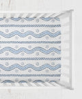 A fitted sheet with a blue and white geometric pattern, shown inside a white wooden crib. Andrew Blue and White Stripes Crib Sheet - The Creative Raccoon 