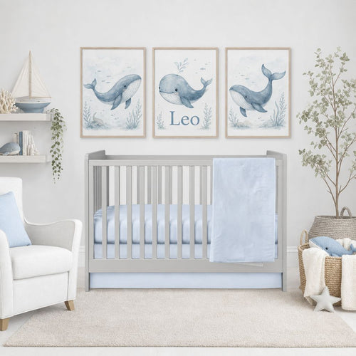 A styled nursery scene with a light gray wooden crib, pale blue bedding, and three framed whale prints above the crib. The prints include the name Leo and are shown in a real room setting with a chair, shelf, basket, and plant.

Baby Boy Crib Bedding Light Blue - The Creative Raccoon 