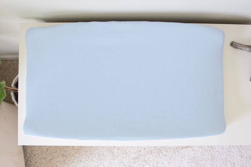 a changing pad cover in light blue over a change pad on a white dresser. 
Baby Blue Changing Pad Cover - The Creative Raccoon
