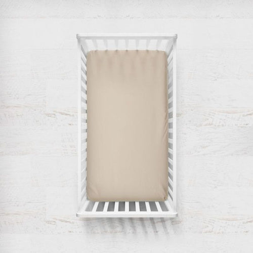 White crib with beige sheet on a light wooden floor.
Beige Crib Sheet - The Creative Raccoon