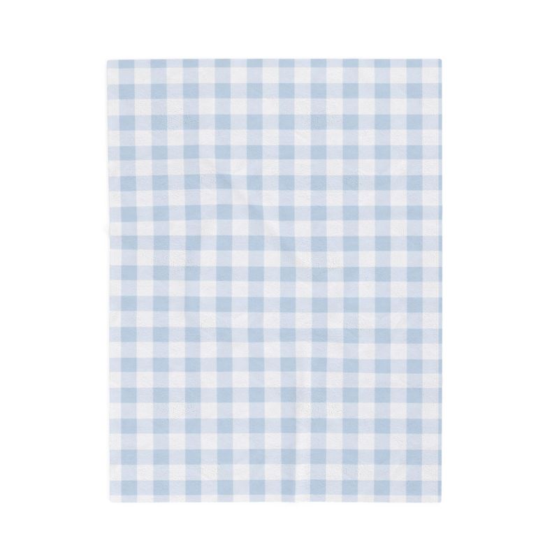 A folded minky baby blanket featuring a light blue and white gingham check pattern on one side and a solid white plush backing on the other, shown on a clean white background.