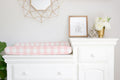 White dresser with pink checkered changing pad, framed picture, and decorative items in a nursery. Changing Pad Cover Light Pink Gingham - The Creative Raccoon