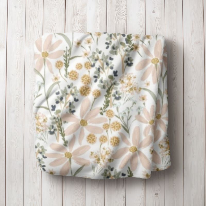 Daisy Floral-patterned blanket on a wooden surface. Daisy Baby Blanket - The Creative Raccoon