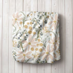 Daisy Floral-patterned blanket on a wooden surface. Daisy Baby Blanket - The Creative Raccoon