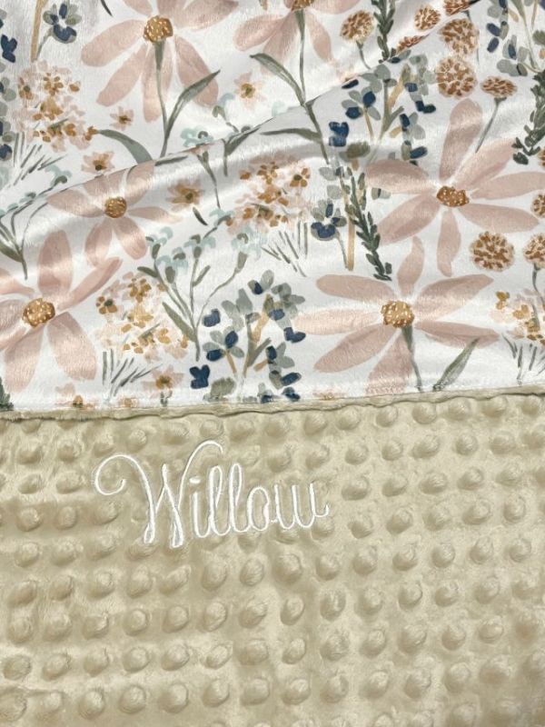 Floral patterned blanket with 'Willow' branding on a textured beige surface. Daisy Baby Blanket - The Creative Raccoon