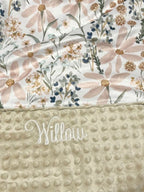 Floral patterned blanket with 'Willow' branding on a textured beige surface. Daisy Baby Blanket - The Creative Raccoon