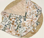 Floral-patterned blanket on a woven surface. Daisy Baby Blanket - The Creative Raccoon