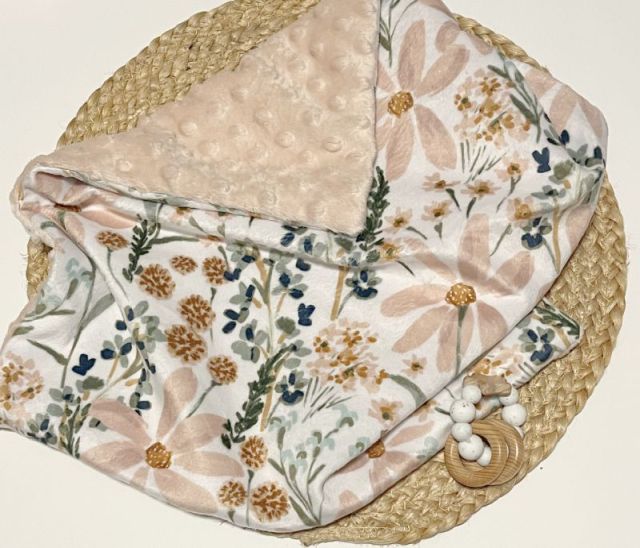 Floral-patterned blanket on a woven surface. Daisy Baby Blanket - The Creative Raccoon