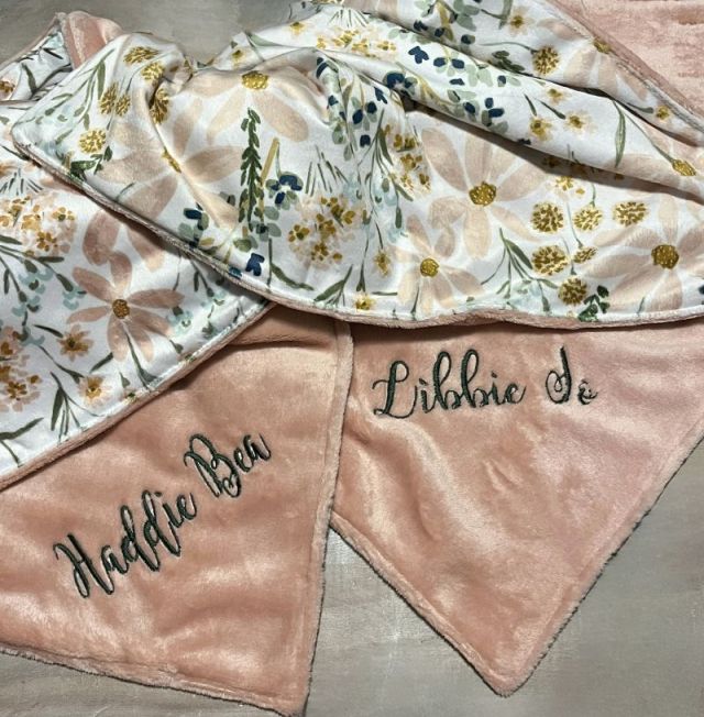 Floral-patterned blanket with embroidered names on a neutral background.  Daisy Baby Blanket - The Creative Raccoon