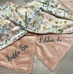Floral-patterned blanket with embroidered names on a neutral background.  Daisy Baby Blanket - The Creative Raccoon