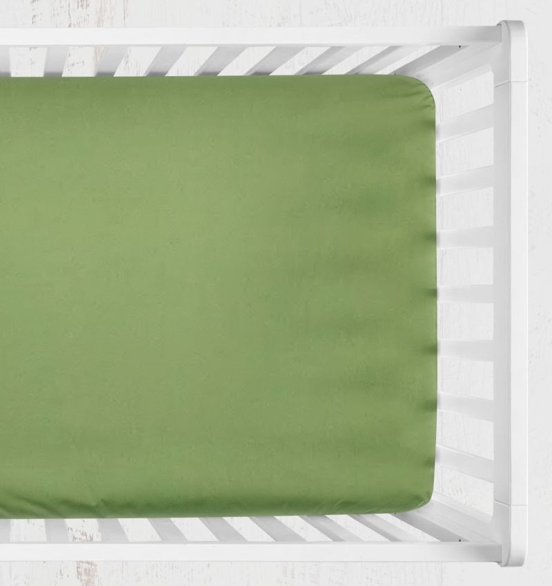An green fitted sheet on a mattress inside a white wooden crib, shown from a top-down perspective against a white textured wall. Green Crib Sheet - The Creative Raccoon