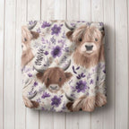 Floral-patterned blanket with highland cow design on a wooden surface. 
Highland Cow Baby Blanket - The Creative Raccoon