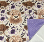 Floral patterned fabric with highland cow heads and a purple blanket. Highland Cow Baby Blanket - The Creative Raccoon