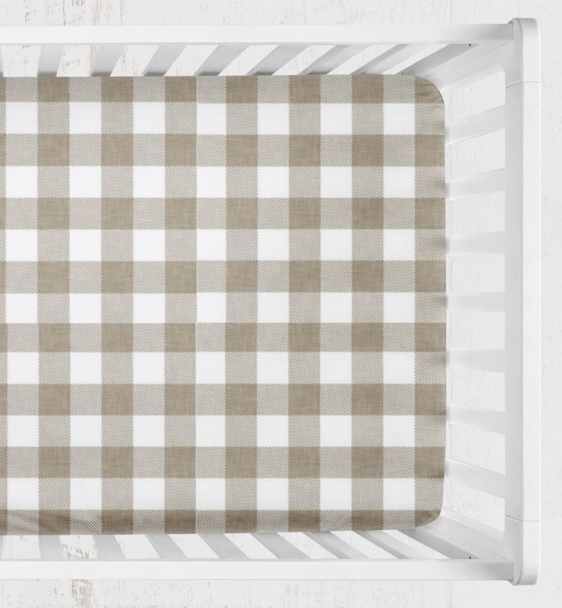 A fitted crib sheet with a classic brown and white gingham check pattern, shown inside a white wooden crib. Khaki Gingham Crib Sheet 2 inch squares - The Creative Raccoon