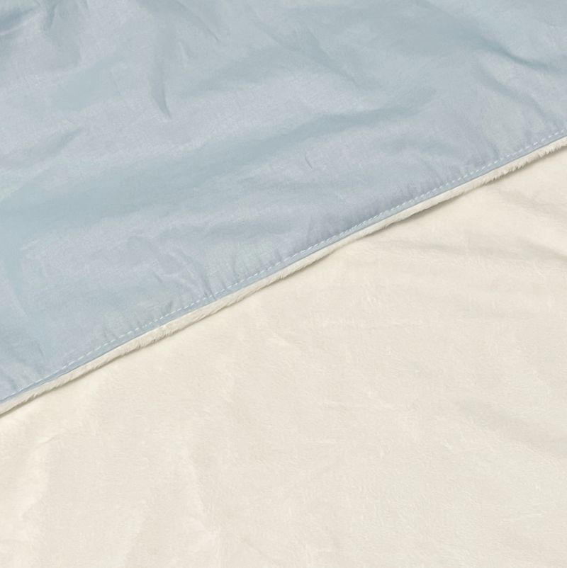 A close-up of a light blue baby blanket with soft plush white minky showing the texture and stitching.
Light Baby Blue Cotton Baby Blanket - The Creative Raccoon 
