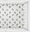 A white crib fitted sheet with a repeating pattern of mallard ducks, shown inside a white wooden crib. Mallard Duck Crib Sheet - The Creative Raccoon