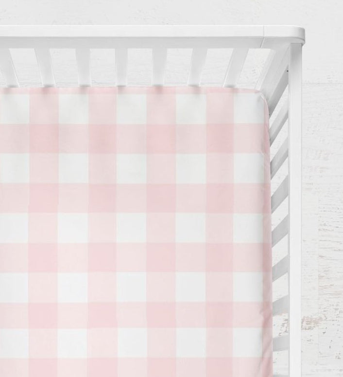 Crib with pink and white checkered fitted sheet on a light wooden floor.
Pink Gingham Crib Sheet - The Creative Raccoon