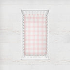 Crib with pink and white checkered fitted sheet on a light wooden floor.
Pink Gingham Crib Sheet - The Creative Raccoon