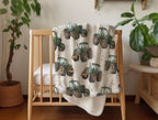 A soft minky fleece blanket featuring a repeating pattern of green farm tractors on a cream background, draped over a light wood crib in a styled nursery setting with potted plants.
Tractor Minky Blanket with Cream Background - The Creative Raccoon