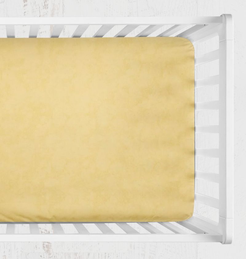 A pale yellow fitted sheet displayed inside a white wooden crib, viewed from a top-down perspective against a white textured background. Yellow Crib Sheet, Buttercup, Boy or Girl Nursery - The Creative Raccoon