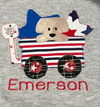 Applique example - Children's shirt with a dog in a wagon, American flag design, and 'Emerson' text on a gray background. - the creative raccoon